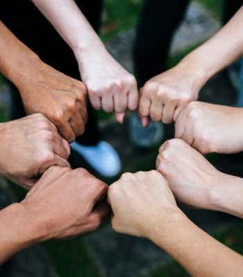 Close up of students standing hands making fist bump gesture.